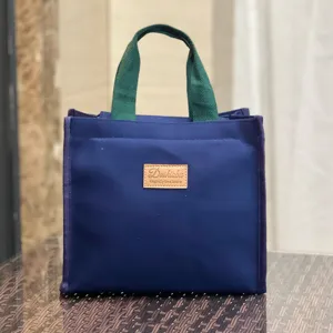 Borsa portapranzo in tela blu con manici verdi e toppa in pelle, tote bag comoda e pratica.