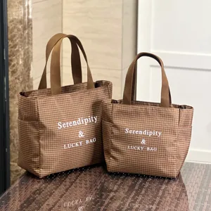 Detail view of brown checkered canvas tote bag, featuring sturdy handles and spacious interior.