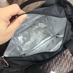 Interior detail of black insulated lunch bag featuring thick silver thermal lining and zipper.