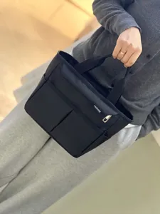 Detailed view of black multi-pocket lunch bag, showing fabric texture and front storage.