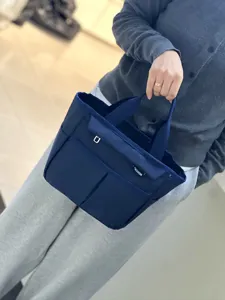 Multi-pocket dark blue lunch tote bag detail showing outer compartments and sturdy fabric handles.