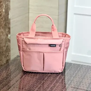 Pink multi-pocket waterproof tote bag detail showing fabric texture and front label.