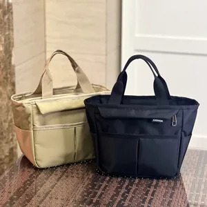 Waterproof insulated lunch bag with multiple pockets, durable canvas commuter bento handbag.
