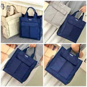 Multi-pocket canvas tote bag detail, featuring front flap pockets and side mesh storage.