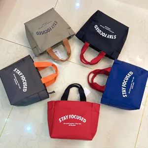 Detailed view of multi-color Oxford cloth lunch bags with contrast handles and bold lettering.