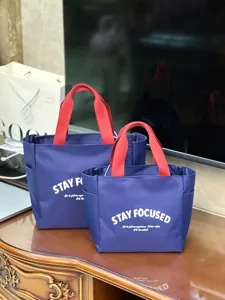 Nahaufnahme von zwei blauen Lunch-Taschen mit roten Griffen für das tägliche Pendeln.