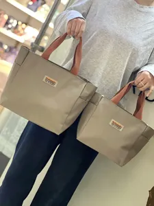 Detailaufnahme der stilvollen Oxford-Stoff-Tragetasche mit robusten braunen Griffen.