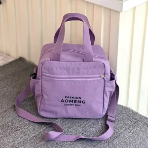 Close-up detail of the purple lunch tote bag with shoulder strap, showing fabric and front zip.