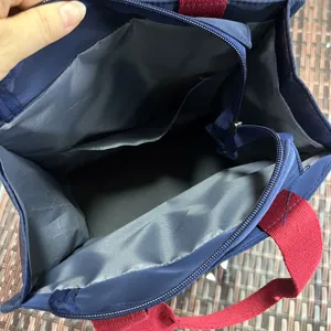 Interior detail view of blue lunch tote bag with red handles showing ample storage space.