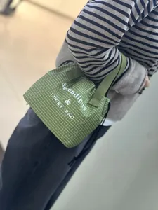Détail de sac bento à carreaux verts avec tissu imperméable et cordon de serrage.