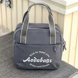 Vue détaillée du sac de voyage en tissu oxford gris, poche avant et poignées robustes.