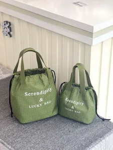 Gros plan sur les sacs cabas étanches à cordon de serrage et carreaux en deux tailles.