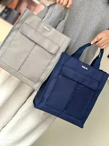 Detail view of multi-pocket canvas tote bags in grey and blue showing functional front pockets.