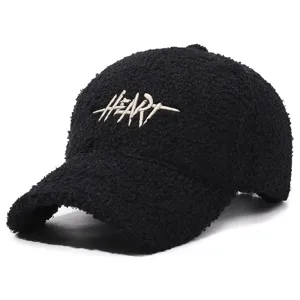 Detailed view of black teddy fleece baseball cap with white embroidered heart letter design.