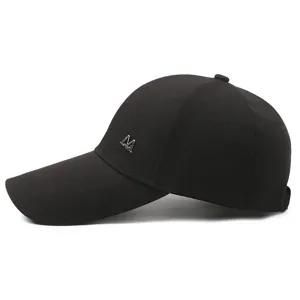 Close-up detail of the black baseball cap showing the extended brim and metallic M logo accent.