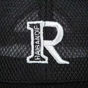 Close-up detail of black mesh baseball cap with white embroidered R letter and brand text.