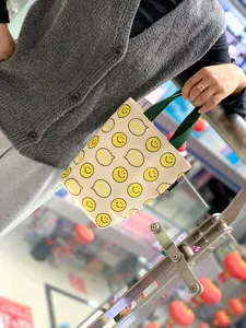Detailed shot of cute smiley face canvas tote bag, perfect for carrying cups and snacks.