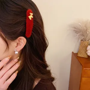 Chic red plush hair clip with cute gold pony detail and pearl earrings, elegant detail view.