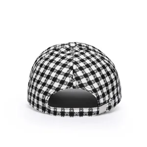 Gorra de béisbol con estampado de cuadros blancos y negros, detalle trasero con hebilla metálica.