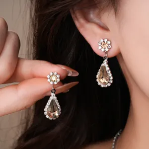 Primer plano detallado de pendientes colgantes de flor de diamantes de imitación y lágrima en la oreja.