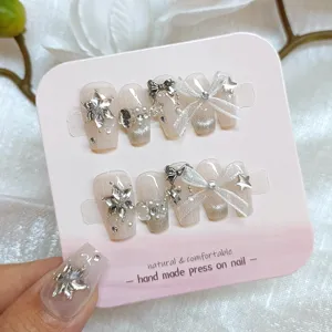 Uñas postizas hechas a mano con lazos dulces y pedrería brillante para un estilo único.