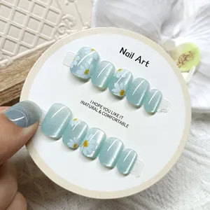 Closeup of handmade short cat-eye press-on nails with sweet white daisy floral art.