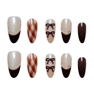 Primer plano detallado de uñas postizas hechas a mano con lazos bonitos y purpurina.