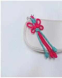 Handmade woven pink and turquoise butterfly knot bag charm keychain detail view