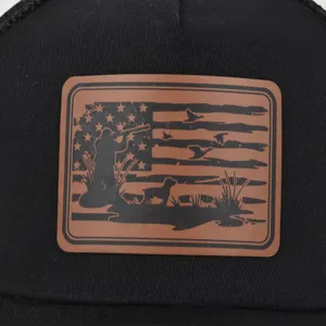 Close-up detail of black mesh trucker hat featuring outdoor hunting leather patch design.