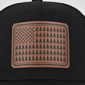 Gros plan élégant de la casquette noire avec un patch en cuir motif drapeau et sapins.