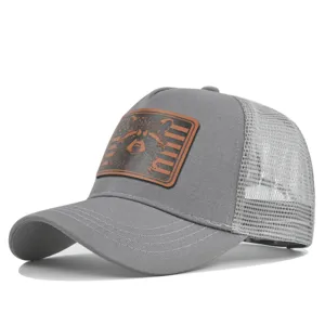 Detail view of gray trucker hat featuring a textured brown leather patch with raccoon graphic.