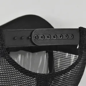 Primo piano della chiusura regolabile in plastica e della retina nera traspirante di un cappello.