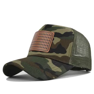 Détail de casquette trucker camouflage en filet avec patch en cuir marron et motif d'arbres.