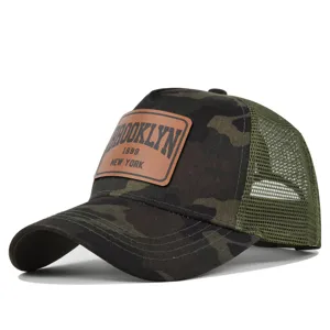 Close up detail of camouflage mesh trucker hat featuring brown leather Brooklyn patch.