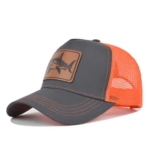 Primer plano detallado de la gorra trucker gris y naranja con parche de tiburón de cuero.
