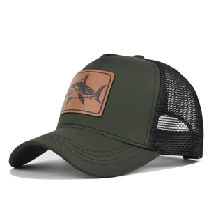 Detalle de gorra trucker verde militar con parche de tiburón de cuero y malla trasera.