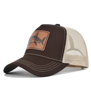 Detalle de gorra trucker de malla marrón, con parche de tiburón de cuero elegante.