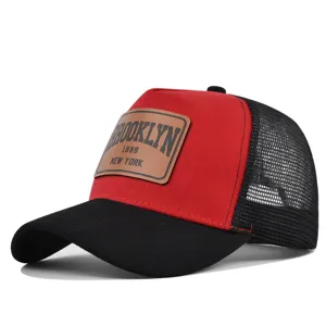 Red and black trucker hat with brown leather patch, breathable mesh back and curved brim.