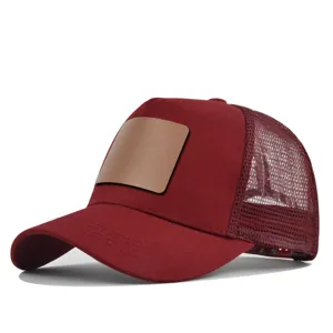 Detailopname van de bordeauxrode truckerpet met blanco lederen patch en ademend mesh.