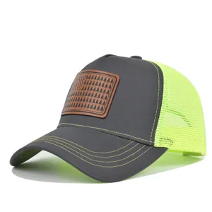 Casquette trucker grise avec filet jaune fluo et un patch en cuir marron motif drapeau sapin.