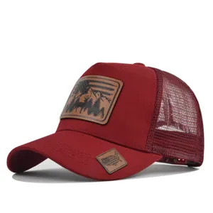 Detailed view of burgundy mesh trucker hat with decorative deer mountain leather patch and visor tag.