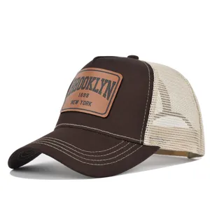 Close up detail of the brown mesh trucker hat featuring front leather patch branding elements.
