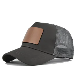 Zwarte trucker pet met blanco lederen patch en ademende mesh achterkant design.