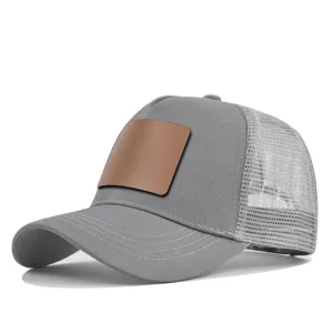 Grijze mesh trucker pet detail met blanco bruine lederen patch en ademend netwerk achterop.