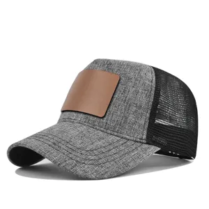 Detailopname van de grijze truckerpet met een blanco bruine lederen patch en zwart mesh.
