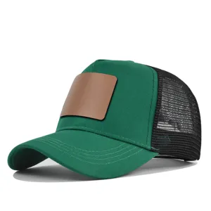 Detail van groen truckerpetje met bruine lederen patch en ademende mesh achterkant.