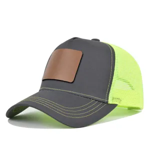 Grijs trucker baseballpet detail met neongeel mesh achterkant en bruine lederen patch.