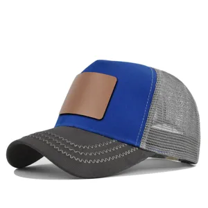 Detailopname van de blauwe en grijze truckerpet met blanco bruine lederen patch aan de voorkant.