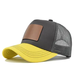 Detailopname grijze gele truckerpet met blanco lederen patch en ademende mesh achterkant.