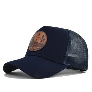 Vista detallada en primer plano de una elegante gorra de malla azul marino con parche de cuero.